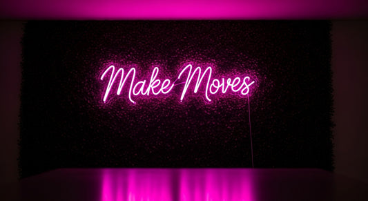 Make Moves neon sign in pink on grass wall