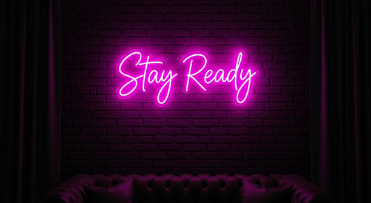 Stay Ready neon sign in pink on brick wall